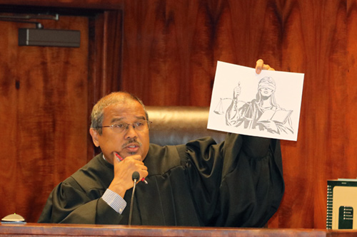 Oahu Judge William Domingo shows a sketch of Lady Justice to 8th grade students who visited his courtroom at the First Circuit Court Building on March 7, 2017. Judge Domingo used the sketch to explain the Judiciary’s role in applying the rule of law equally for all people.