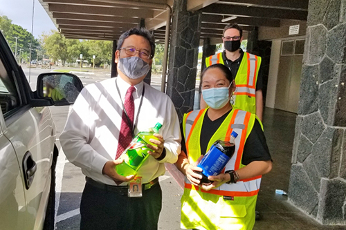 Hilo Drug Court Judge Henry Nakamoto (left), Friends of Big Island Drug Court Vice President Michelle Manalo, and Drug Court Probation Officer Dustin Cueva (back) at the 03/02/21 Hilo Civic Center food distribution event.